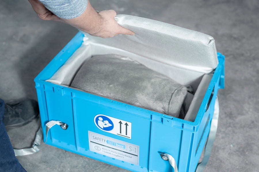 En hÄnd Äbner en blÄ kasse med en blÞd pude, grÄt indhold, neutralt miljÞ.