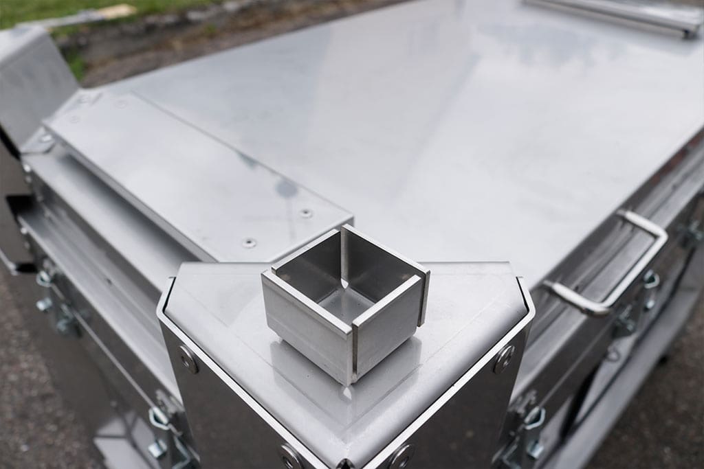 Industriel metalkasse med sølvfarvet overflade, kantet form og detaljeret konstruktion.