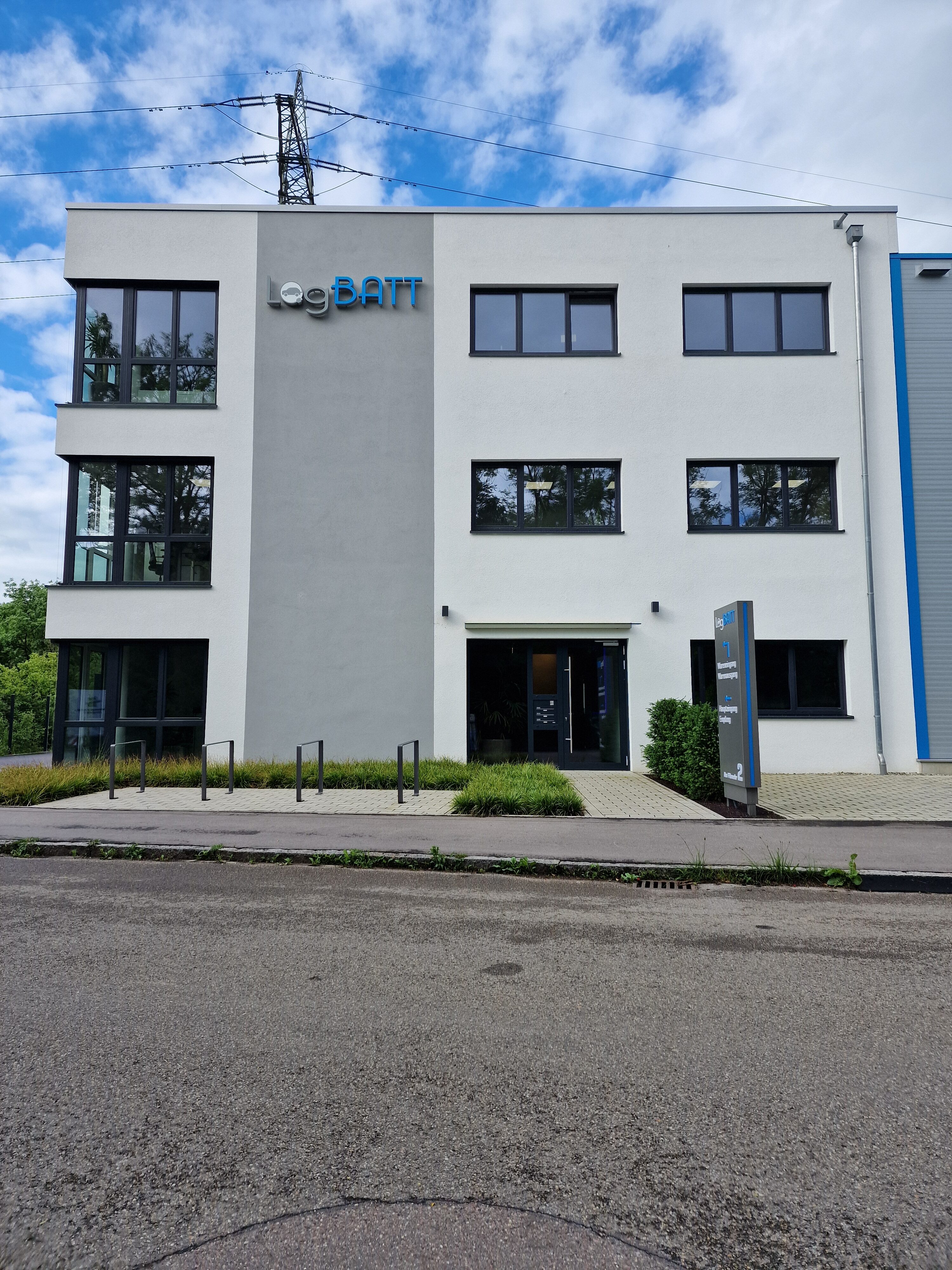 En moderne kontorbygning med hvid facade og store vinduer på en overskyet dag.